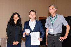 A photo of Felix Glang standing next to Asifa Akhtar, vice president of the MPG, and Klaus Scheffler