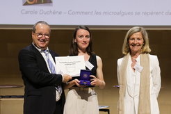 Carole Duchêne receiving her prize in the auditorium of the Institut de biologie physico-chimique in Paris, with Daniel Choquet, French Neuroscientist, and the French bacteriologist Pascale Cossart by her side.